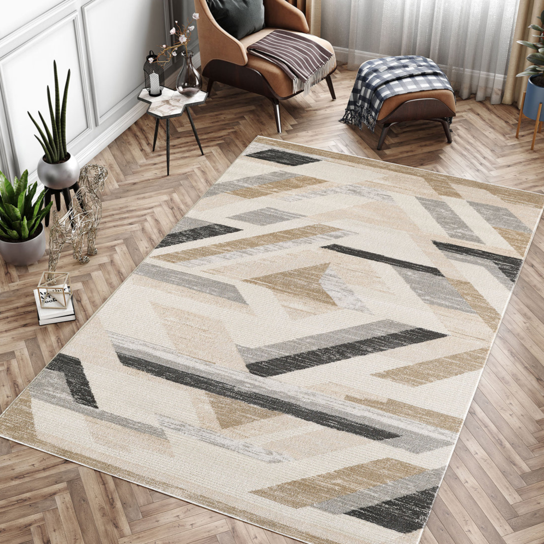 A modern area rug with a geometric pattern in neutral tones is placed on a herringbone wood floor, accompanied by a tan armchair with a matching ottoman, houseplants, and a small side table.
