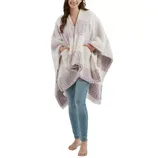 A woman is wearing a cozy, oversized sherpa plaid poncho in shades of white and light gray, paired with light blue skinny jeans.
