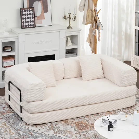 Beige corduroy sofa with three pillows and a black metal support bar, set in a cozy living room featuring a white mantelpiece, decorative items, and a patterned rug.