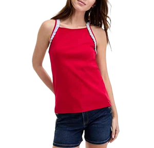 A woman is wearing a red sleeveless top with white lace straps and blue denim shorts.