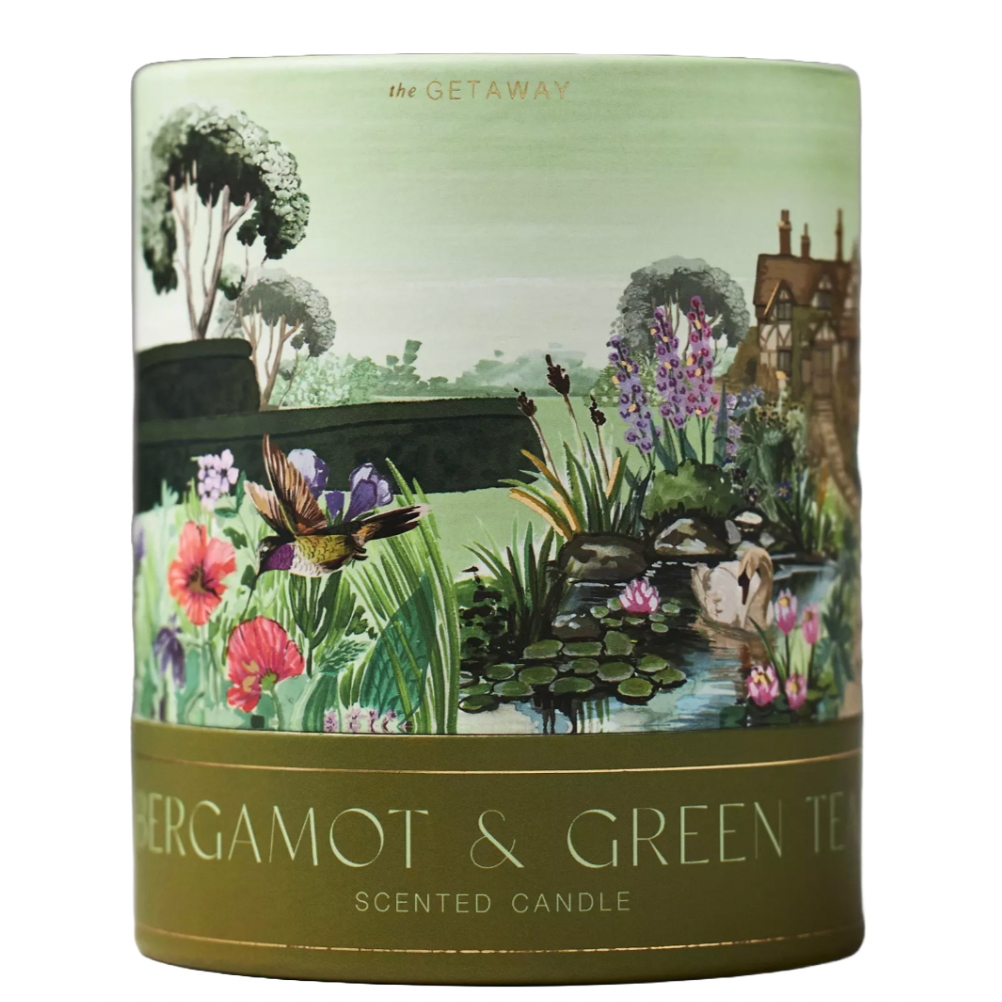 Scented candle labeled \“Bergamot & Green Tea\“ from \“The Getaway\“ series, featuring a decorative illustration of a garden scene with plants, flowers, a bird, and a pond.