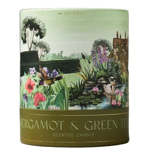 Scented candle labeled \“Bergamot & Green Tea\“ from \“The Getaway\“ series, featuring a decorative illustration of a garden scene with plants, flowers, a bird, and a pond.