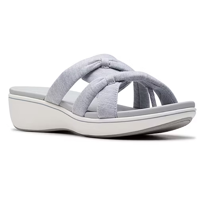 Clarks Breeze Rae Sandals feature a cushioned wedge sole with criss-cross fabric straps in light gray, offering a comfortable and casual slip-on style.