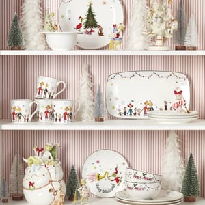 Festive dishware collection featuring characters from a popular holiday story, displayed with holiday-themed decorations like miniature trees and figurines.