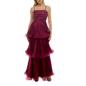 A sleeveless, floor-length gown in rich maroon with spaghetti straps, featuring a tiered, pleated design with a layered bodice and full skirt.