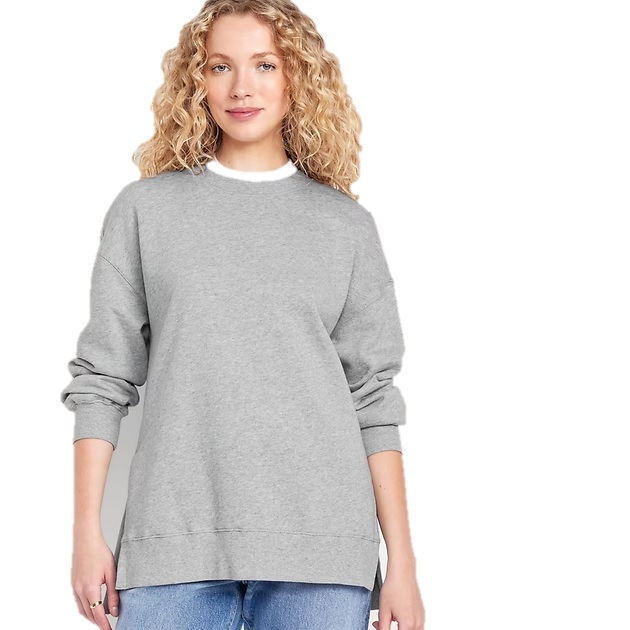 A person is wearing a gray oversized sweatshirt with rolled-up sleeves and blue jeans. The sweatshirt has a crew neck design.