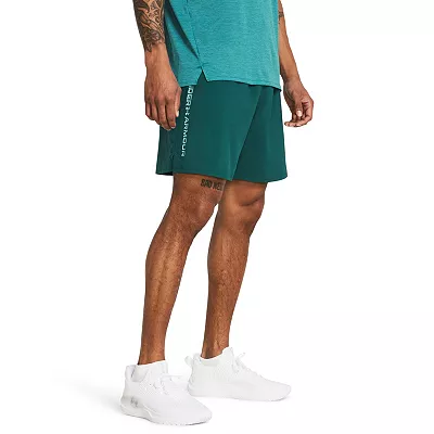 Green shorts with a logo on the right leg, above the hem, paired with a teal top and white sneakers.