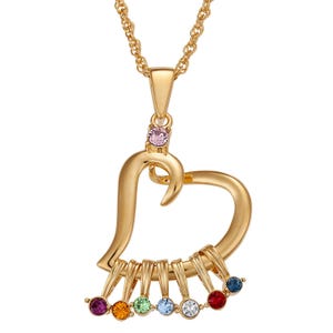 A gold heart-shaped charm necklace adorned with a pink stone above and seven multi-colored birthstones (purple, orange, green, light blue, clear, red, and dark blue) dangling below on a gold chain.