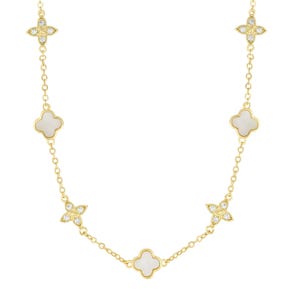 The Adornia Clover Station Necklace features gold chain links interspersed with white mother-of-pearl clover shapes and diamond-like accents in a floral motif. The design blends elegance and simplicity with a luxurious touch.