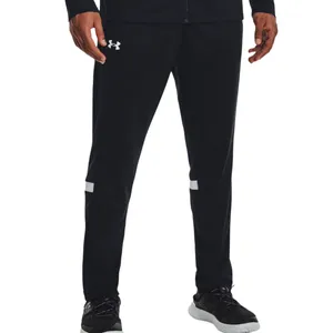 Black athletic track pants with the Under Armour logo on the upper left thigh, featuring white stripes above the knees, paired with black athletic shoes with white soles.