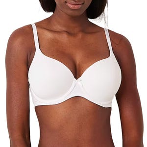 A woman is wearing a white underwire bra with smooth cups and adjustable straps.