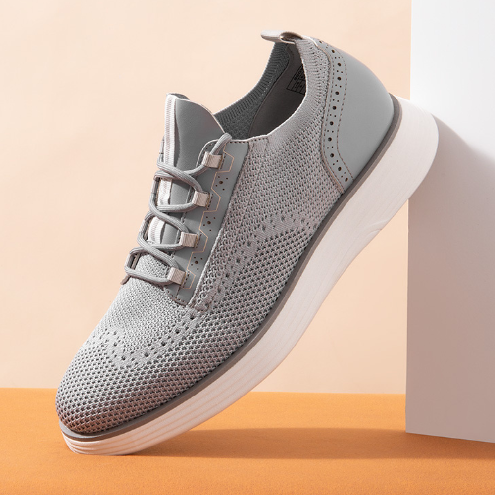 A gray knit sneaker with perforated details and a thick white sole, designed for a modern and casual look.
