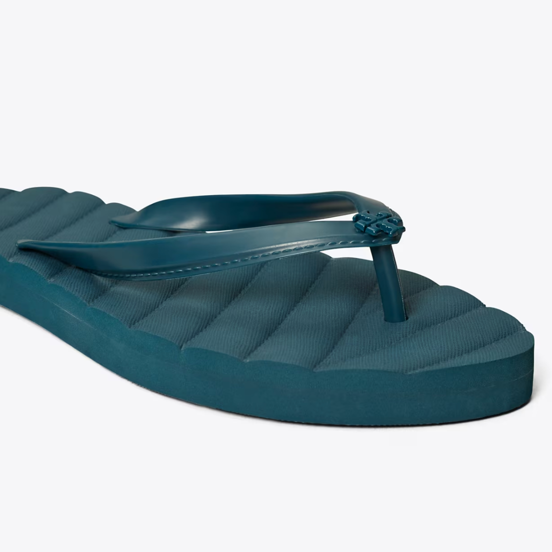 A single teal flip-flop with a platform sole and a flower embellishment on the strap.