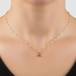 A delicate gold chain necklace with small pearls features a prominent capital letter \“A\“ pendant at the center.
