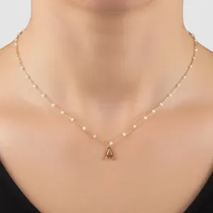 A delicate gold chain necklace with small pearls features a prominent capital letter \“A\“ pendant at the center.