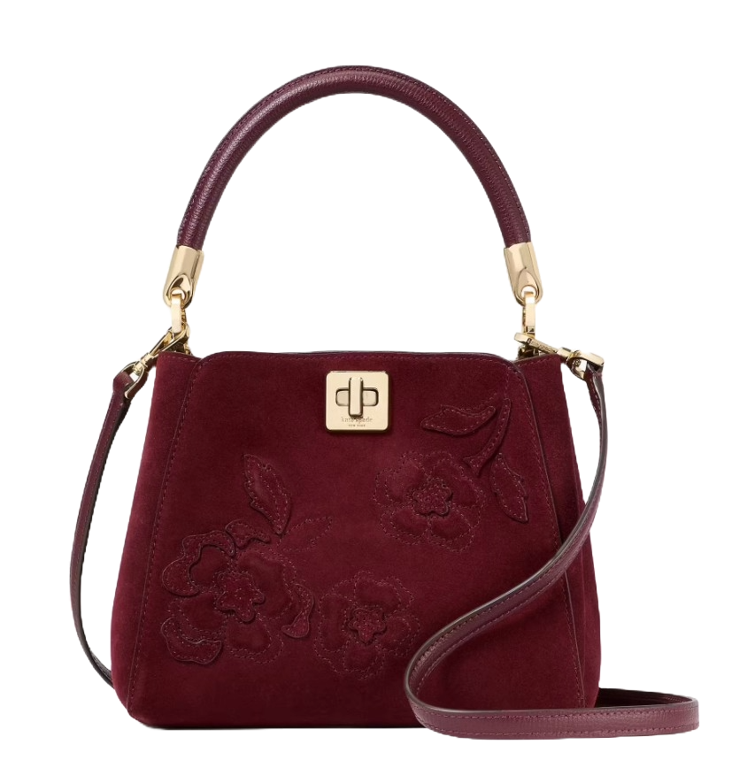 A burgundy handbag with floral embroidery, gold accents, and a top handle. It features a turn-lock closure and an adjustable shoulder strap.