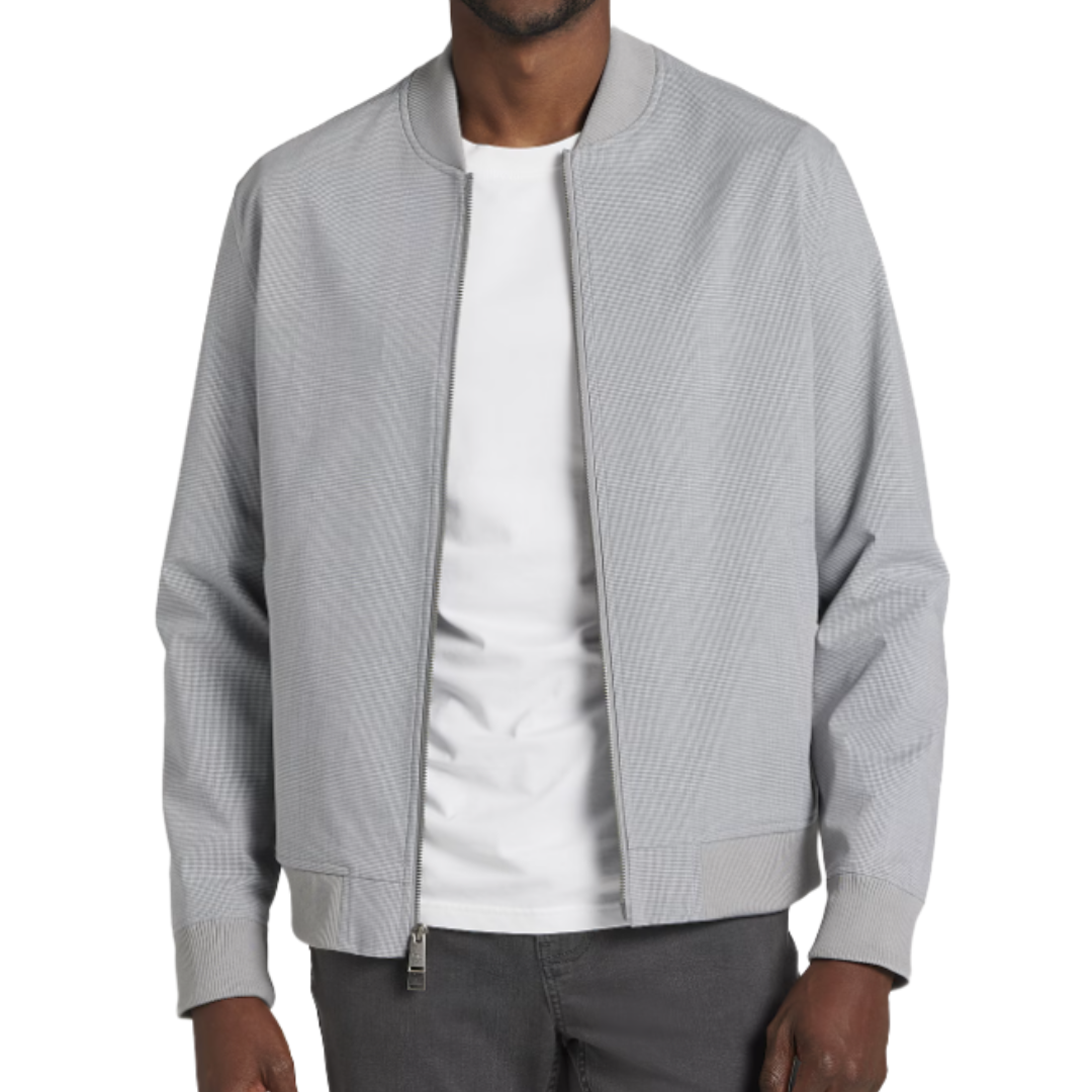A person is wearing a light gray bomber jacket over a white T-shirt, paired with dark gray pants.