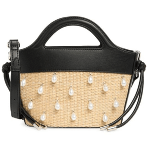 A woven beige handbag with black leather accents and pearl-like embellishments, featuring a top handle and adjustable shoulder strap.