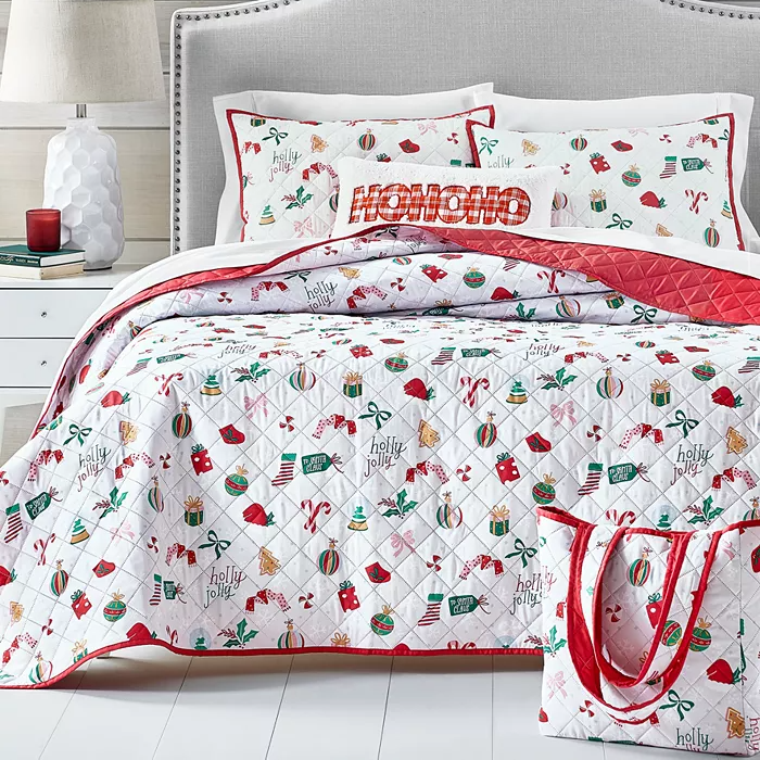 A festive quilt set with holiday-themed patterns, including phrases like \“holly jolly,\“ along with matching pillow shams. The design features red, white, and green colors with presents, holly, and candy canes.