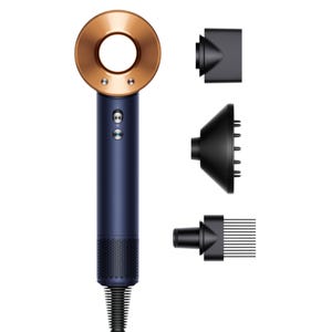 A navy blue and gold hair dryer with a hole in the center, accompanied by three black attachments: a concentrator nozzle, a diffuser, and a comb attachment.