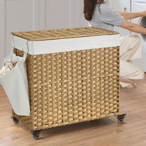 A 160L wicker laundry hamper with a cushioned lid and side pocket, mounted on wheels for mobility.