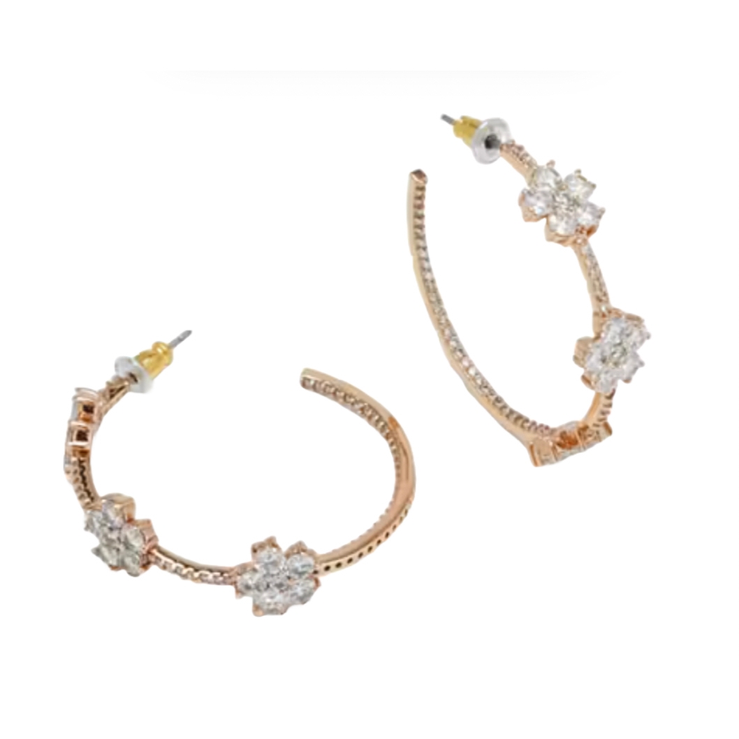 The Kate Spade CZ Flower Hoops are rose-gold-toned hoop earrings adorned with cubic zirconia flowers. They feature a post back closure for secure wear.
