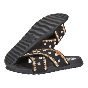 Sandal with adjustable black straps featuring a white and brown floral pattern and a ridged black sole.