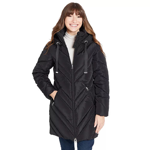 A woman is wearing a black puffer coat with a chevron pattern and a hood. She pairs it with jeans and a white turtleneck.