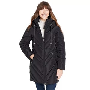 A woman is wearing a black puffer coat with a chevron pattern and a hood. She pairs it with jeans and a white turtleneck.