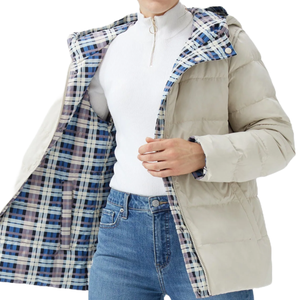 The Orolay Reversible Down Jacket features a beige quilted exterior with a blue and beige plaid lining. It includes a hood and front zipper, and is paired with a white turtleneck and blue jeans.
