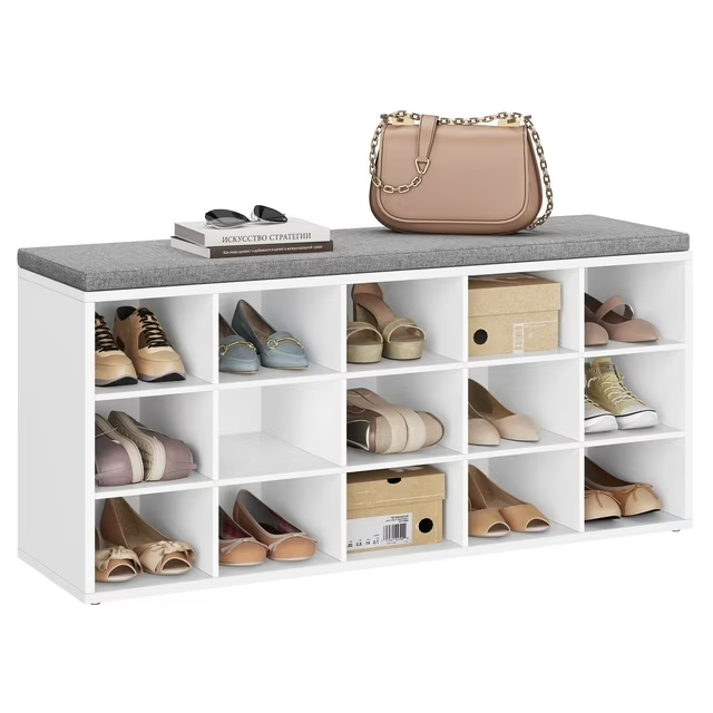 White shoe storage bench with a cushioned top, holding various shoes, a beige handbag, sunglasses, and two books.