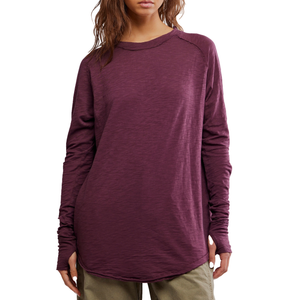 A woman is wearing a long-sleeved, loose-fitting, plum-colored top paired with khaki pants.