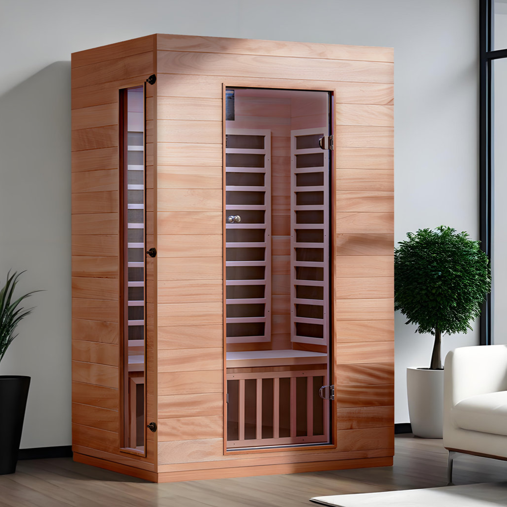 A wooden infrared sauna with a glass door, placed indoors next to a white couch and green plants.