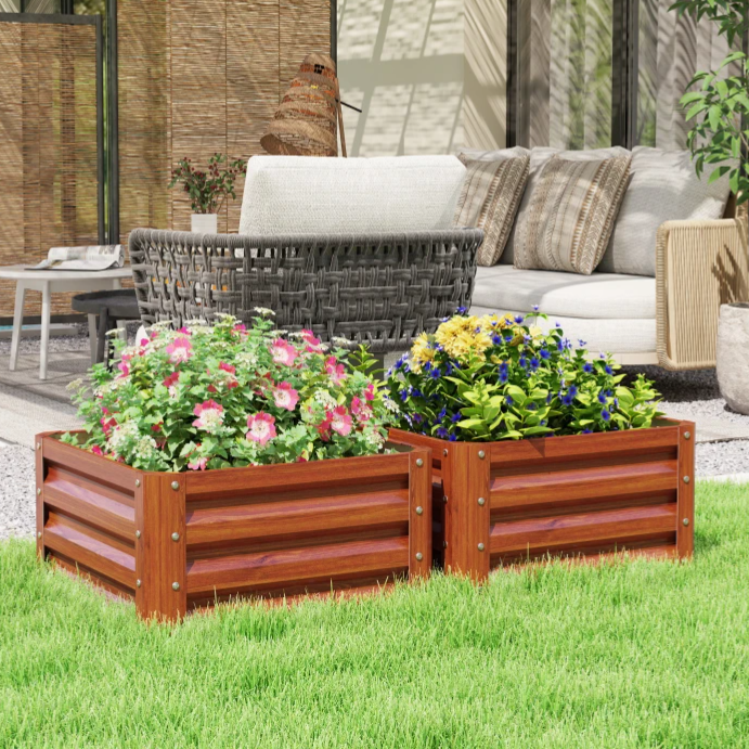 Two wooden raised garden planters filled with colorful flowers are placed on a lawn, with outdoor wicker and rattan furniture in the background.