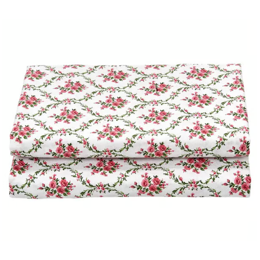 Folded floral-patterned fabric with pink roses and green vines on a white background.
