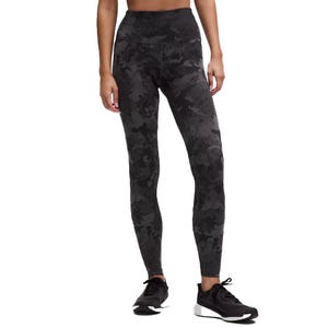 High-waisted leggings with a black camouflage pattern paired with black athletic shoes.