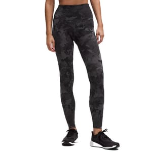 High-waisted leggings with a black camouflage pattern paired with black athletic shoes.