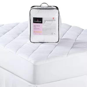 A Cuddl Duds queen mattress pad is presented on a bed, featuring a quilted design with a packaging bag displayed on top.