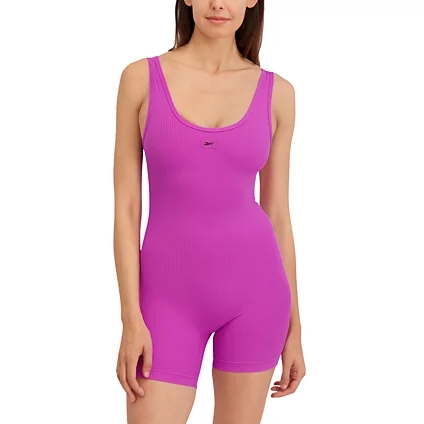 A woman is wearing a purple sleeveless athletic romper with a scoop neckline and mid-thigh length.