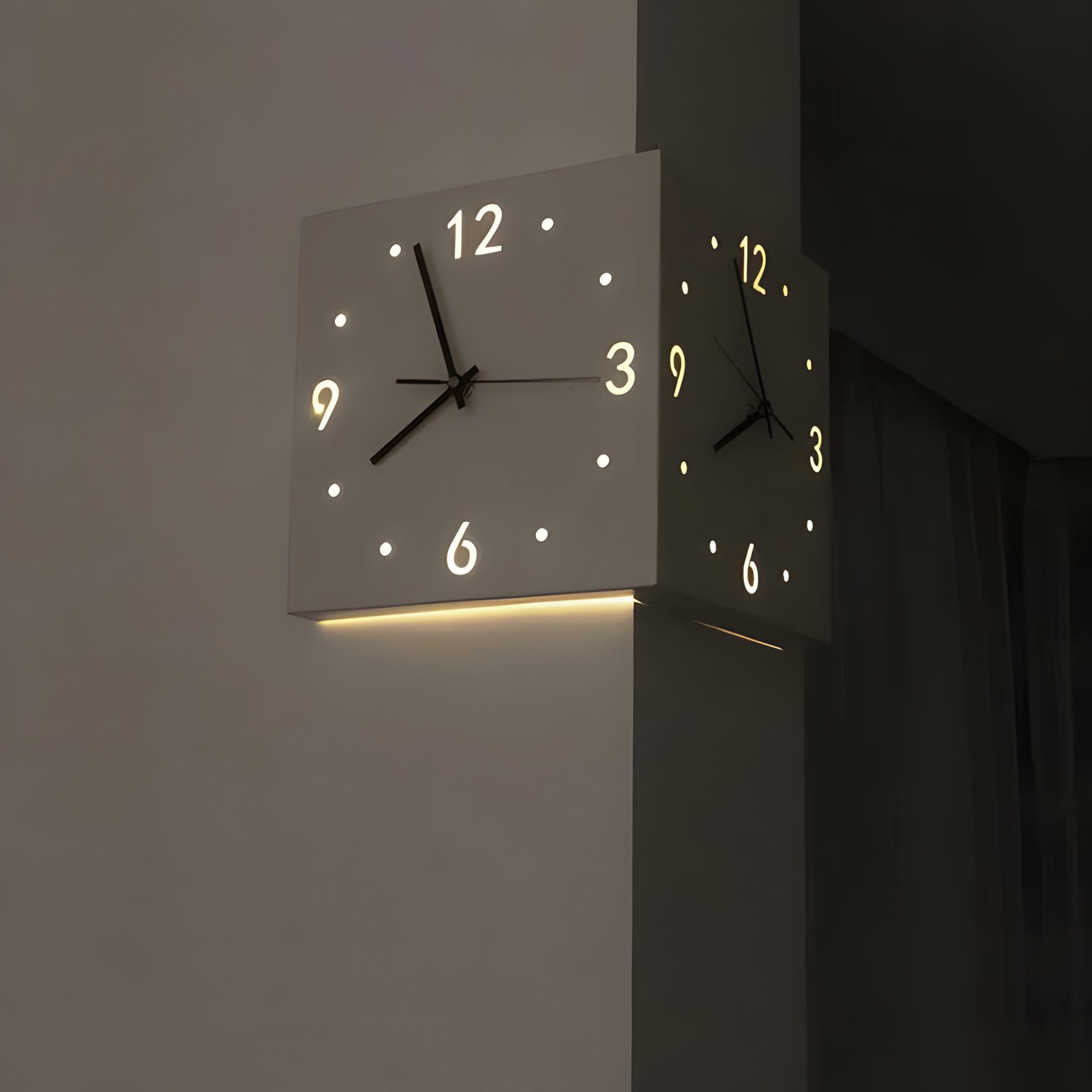 A modern wall-mounted cube clock with illuminated digits and a soft light emitted from its bottom edge.