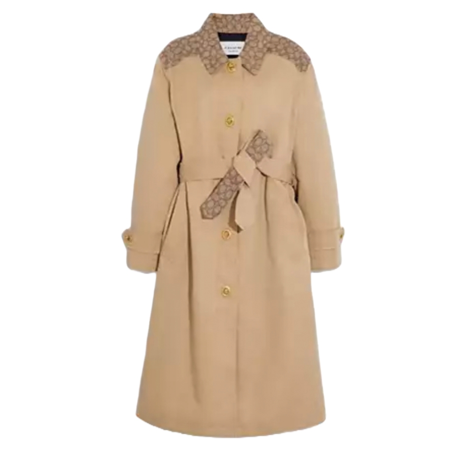 A long beige trench coat with button closure and a sash belt, featuring patterned accents on the shoulders and belt. It has cuffed sleeves and a classic collar design.