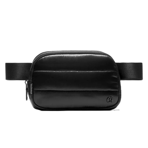 Lululemon Wunder Puff Shine Belt Bag in black features a quilted design with a sleek, shiny finish, adjustable strap, and zippered compartment, offering a stylish and functional accessory for carrying essentials.