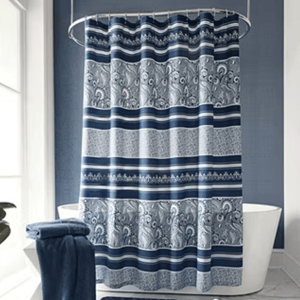 Blue and gray shower curtain with intricate paisley and striped patterns, hanging in a bathroom with matching towels beside a freestanding bathtub.
