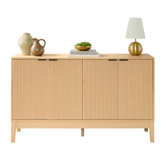 A light wood sideboard with vertical grooves features two pottery vases, two stacked books, a bowl with greenery, and a gold lamp on top.