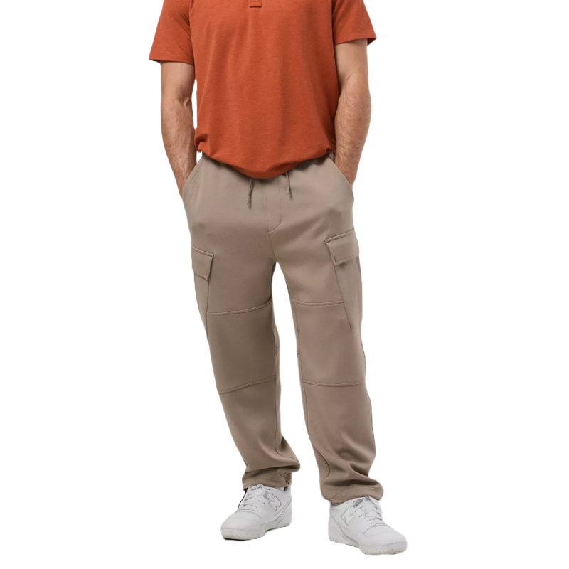 Beige cargo joggers with a relaxed fit, featuring side pockets and an adjustable drawstring waistband. Paired with a rust-colored T-shirt and white sneakers.