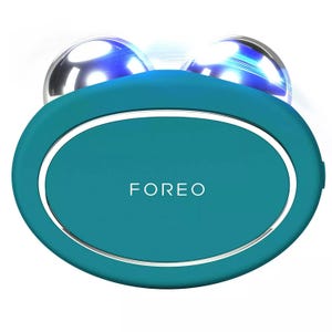 A teal FOREO facial device with two metallic spheres on top, designed for skincare treatment.