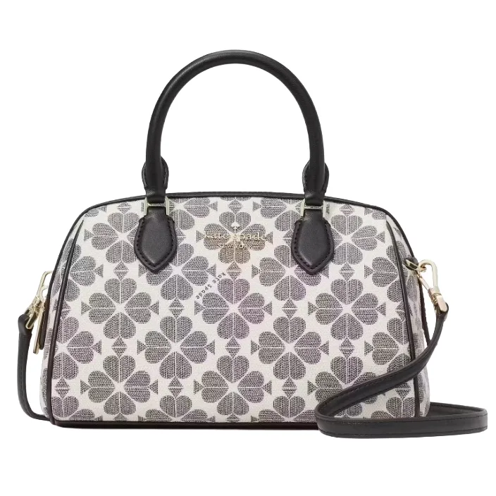 A handbag with a floral pattern in shades of gray and black, featuring dual handles and a detachable shoulder strap. The brand name is displayed on a metal plate on the front.