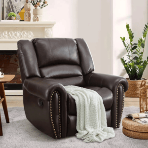 A dark brown recliner chair with nailhead trim, draped with a white chunky knit blanket, is placed on a light-colored rug near a potted plant and decorative basket.