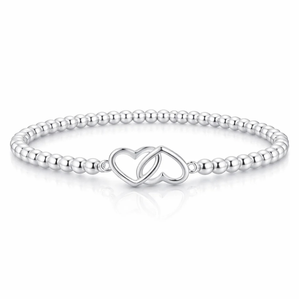 A silver bracelet featuring small round beads and an intertwined double heart charm centerpiece.