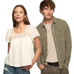 A woman is wearing a white lace-trimmed blouse with short sleeves alongside a man in a khaki button-up shirt over a beige t-shirt and patterned pants.